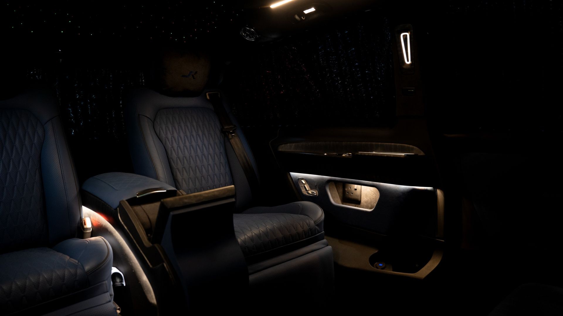 Luxurious car interior with dim lighting, featuring plush blue leather seats and a sleek design.